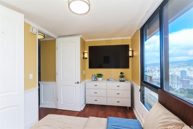 bedroom with a wainscoted wall, dark wood-style flooring, and crown molding