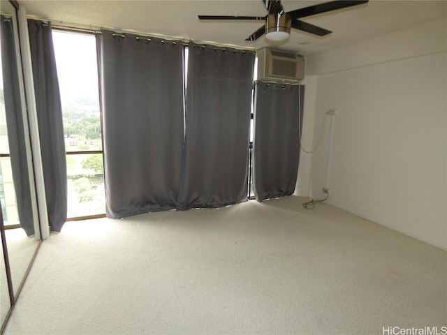 empty room featuring a wall of windows, ceiling fan, and a wall unit AC