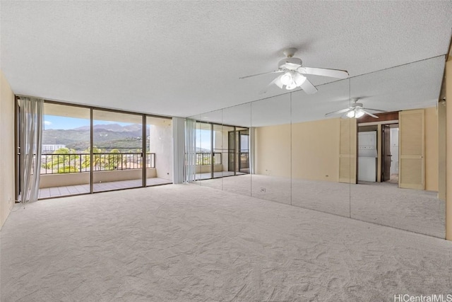 unfurnished bedroom with access to exterior, carpet flooring, a textured ceiling, and a wall of windows