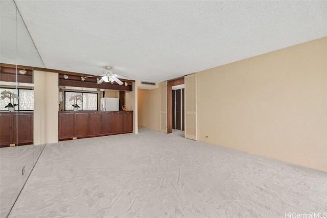 unfurnished living room with visible vents, light colored carpet, a textured ceiling, and a ceiling fan