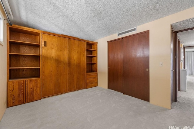 unfurnished bedroom with visible vents, carpet floors, a textured ceiling, and a closet