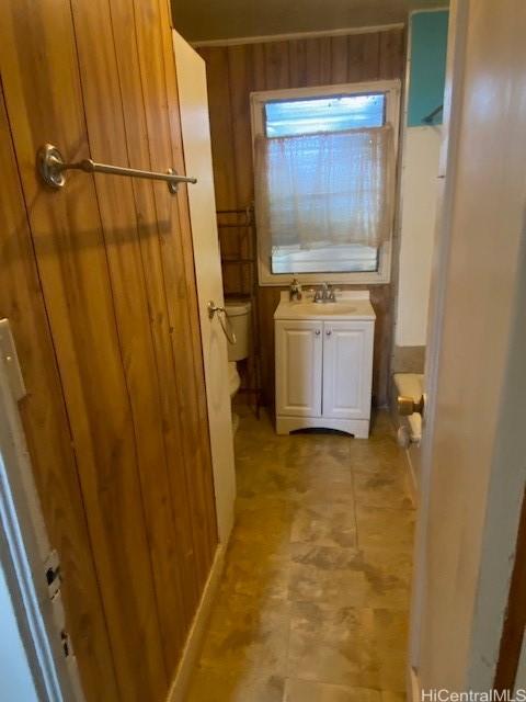 bathroom with vanity, wooden walls, and toilet