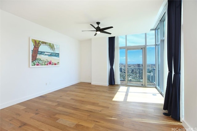 unfurnished room featuring floor to ceiling windows, light wood-style floors, baseboards, and ceiling fan