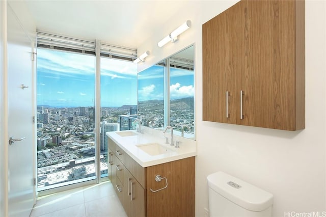 bathroom with double vanity, tile patterned flooring, toilet, and a sink