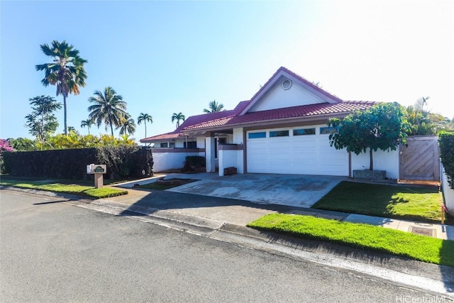 view of front of property featuring driveway, fence, an attached garage, a tile roof, and stucco siding