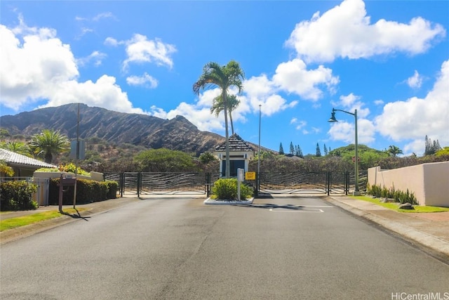 view of road with a mountain view, sidewalks, a gate, and curbs