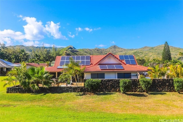view of front of property featuring a front lawn, roof mounted solar panels, a tile roof, and a mountain view