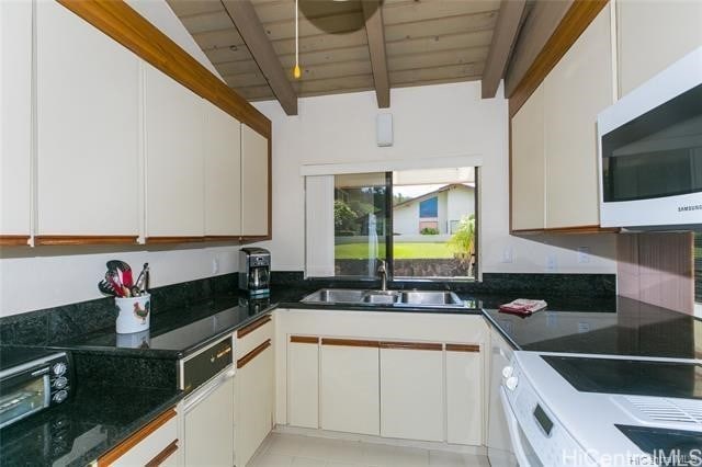 kitchen featuring beam ceiling, white cabinets, a sink, and white microwave