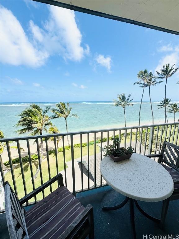 balcony with a water view and a view of the beach