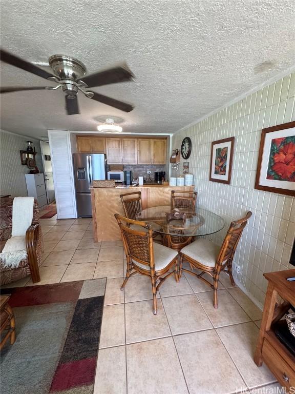 dining space with wallpapered walls, a textured ceiling, light tile patterned floors, and ceiling fan