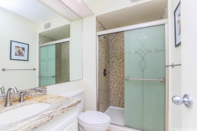 bathroom with visible vents, vanity, toilet, and a shower stall