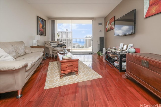 living area with wood finished floors, visible vents, and expansive windows