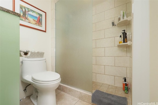 full bathroom featuring tile patterned floors, toilet, and a tile shower