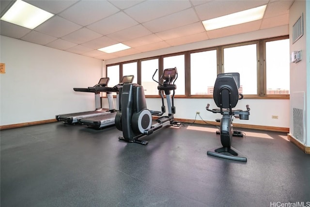 exercise room with a drop ceiling, baseboards, and visible vents