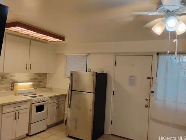 kitchen with tasteful backsplash, light countertops, light tile patterned floors, freestanding refrigerator, and white range with electric stovetop