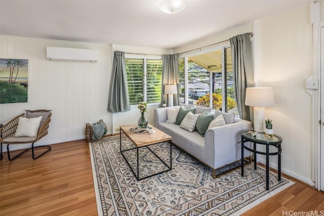 living room with a wall mounted AC and wood finished floors