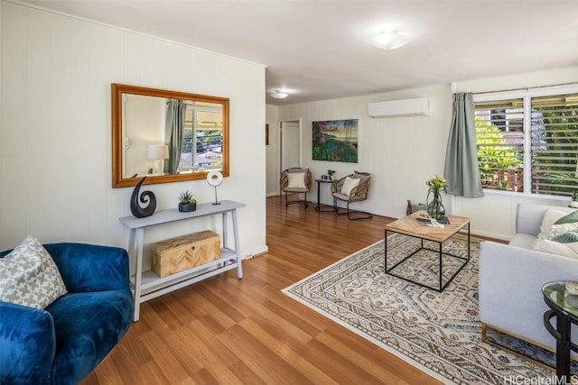 living area with an AC wall unit and wood finished floors