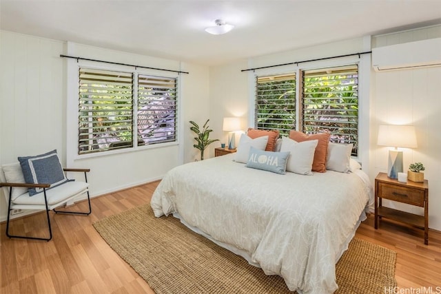 bedroom featuring light wood-style floors and an AC wall unit