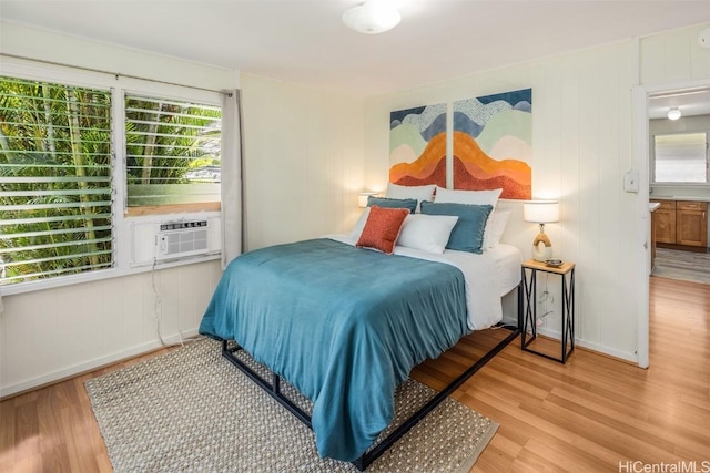 bedroom with cooling unit, baseboards, and wood finished floors