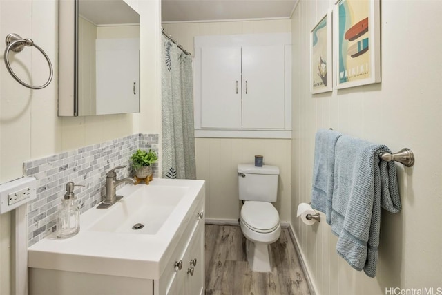 bathroom with vanity, toilet, wood finished floors, and tasteful backsplash