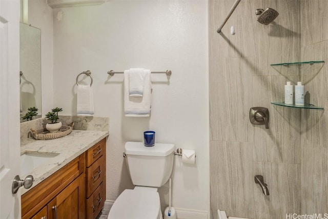 bathroom featuring tiled shower, toilet, and vanity