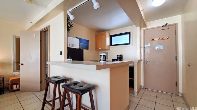 kitchen with light tile patterned floors, a breakfast bar, light brown cabinetry, and light countertops