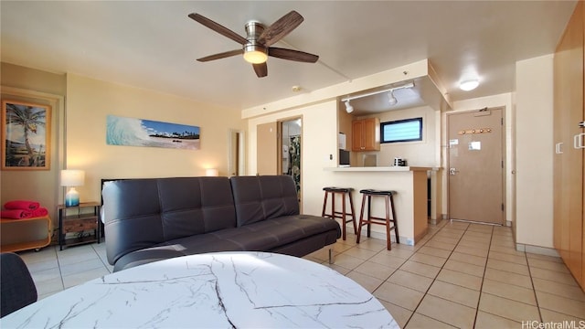 living room featuring light tile patterned floors, baseboards, and ceiling fan