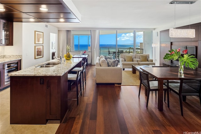 interior space featuring glass insert cabinets, dark wood-style floors, a kitchen bar, wine cooler, and a sink