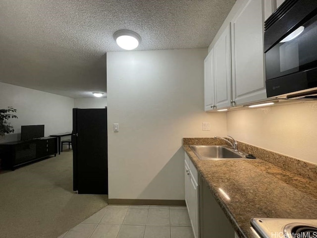 kitchen featuring black appliances, a sink, a textured ceiling, white cabinetry, and light tile patterned flooring