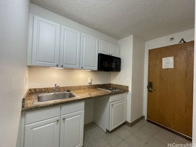 kitchen with dark countertops, white cabinets, black microwave, and a sink