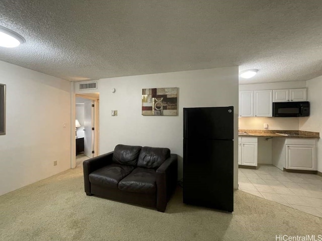 living area with light tile patterned floors, visible vents, light colored carpet, and a textured ceiling