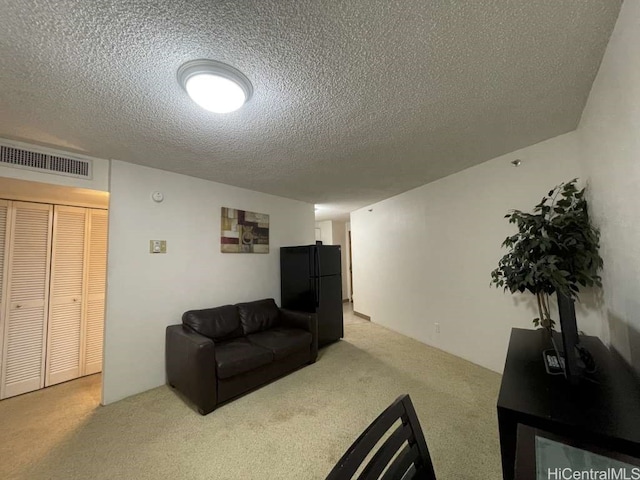 living room featuring visible vents, light colored carpet, and a textured ceiling