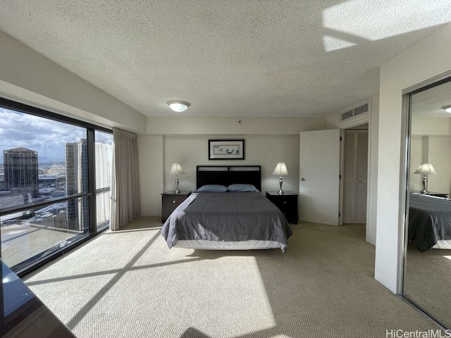 bedroom with visible vents, a textured ceiling, and carpet