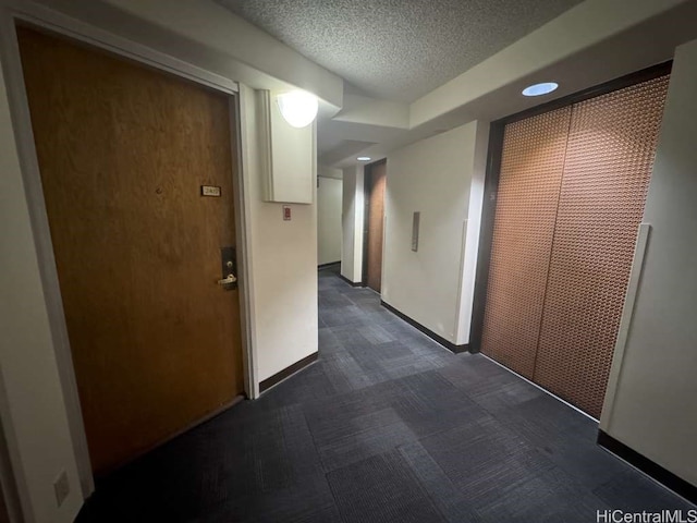 corridor with a textured ceiling and baseboards