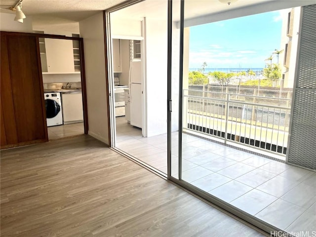 interior space featuring light wood-style flooring, a sink, freestanding refrigerator, rail lighting, and washer / dryer