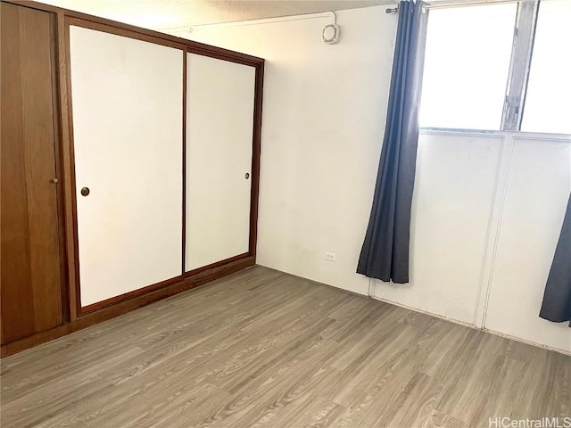 unfurnished bedroom with a closet and light wood finished floors