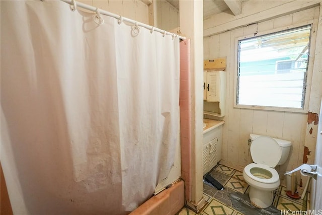 full bath featuring vanity, shower / tub combo, toilet, and wood walls