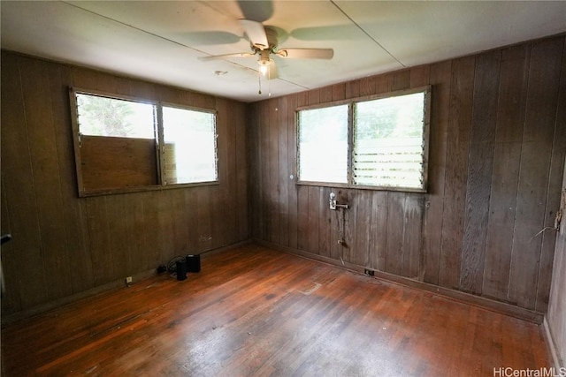 empty room featuring wood finished floors, baseboards, a wealth of natural light, and ceiling fan