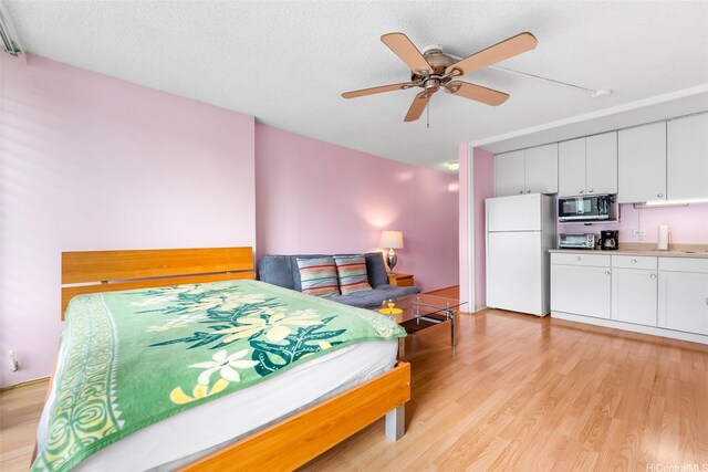 2345 Ala Wai Blvd Unit 1003, Honolulu, HI 96815 - bedroom with freestanding refrigerator, light wood-type flooring, a textured ceiling, and ceiling fan