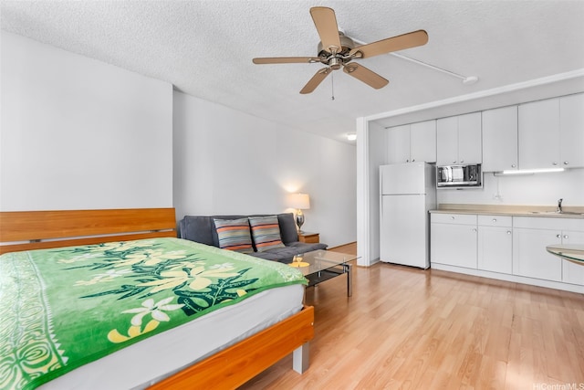 2345 Ala Wai Blvd Unit 1003, Honolulu, HI 96815 - bedroom featuring freestanding refrigerator, light wood-type flooring, a textured ceiling, and a ceiling fan