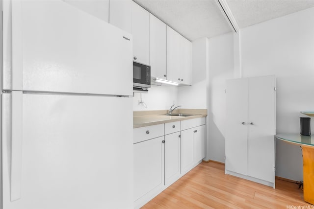 2345 Ala Wai Blvd Unit 1003, Honolulu, HI 96815 - kitchen featuring freestanding refrigerator, light wood-style floors, white cabinetry, and light countertops