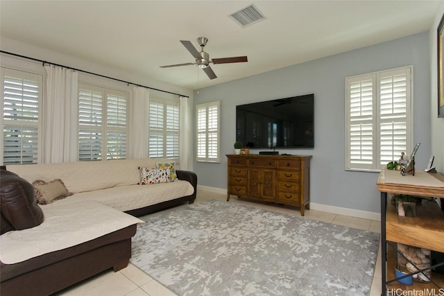 tiled living area featuring visible vents, a healthy amount of sunlight, baseboards, and ceiling fan