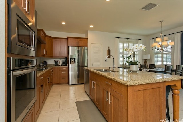 kitchen featuring visible vents, a breakfast bar, light stone counters, appliances with stainless steel finishes, and a sink