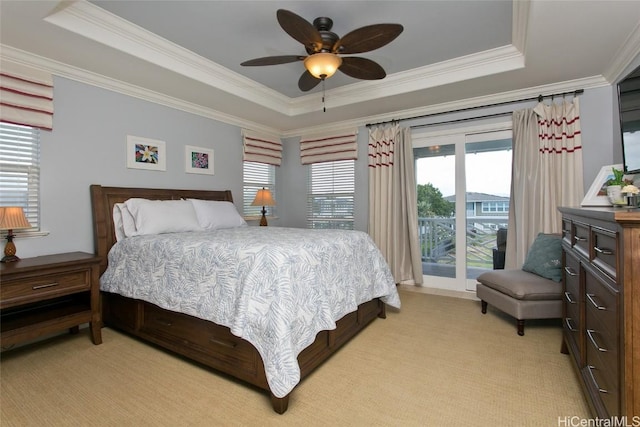 bedroom featuring a tray ceiling, access to exterior, light colored carpet, and ornamental molding