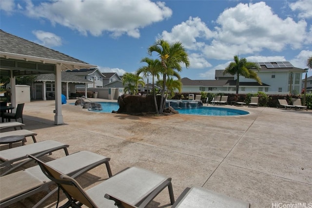 view of pool with a patio, an outbuilding, fence, a pool with connected hot tub, and a residential view