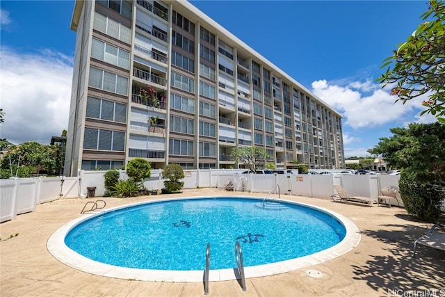 community pool with a patio area and fence