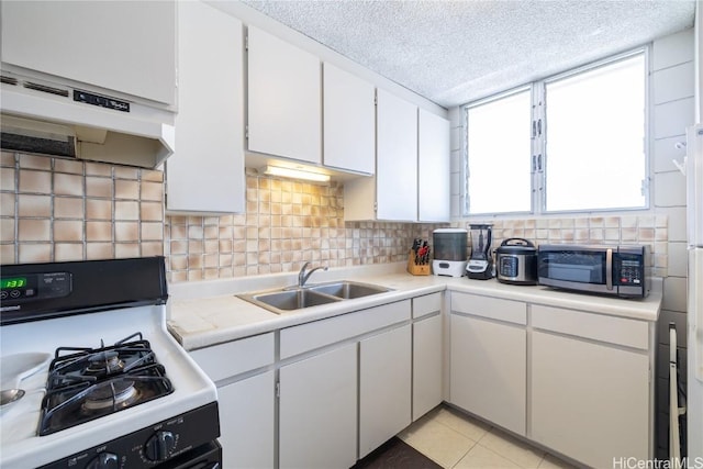 kitchen featuring white cabinetry, a sink, light countertops, range with gas cooktop, and stainless steel microwave