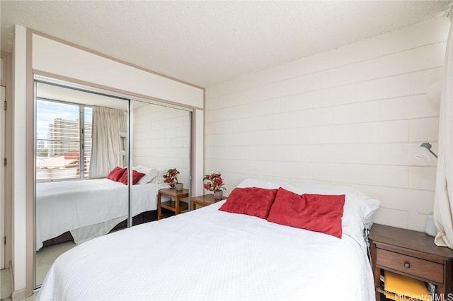 bedroom featuring concrete block wall, a closet, and a textured ceiling