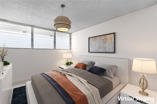 bedroom featuring concrete block wall and a textured ceiling