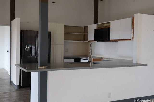 kitchen featuring a peninsula, open shelves, a sink, white cabinetry, and refrigerator with ice dispenser